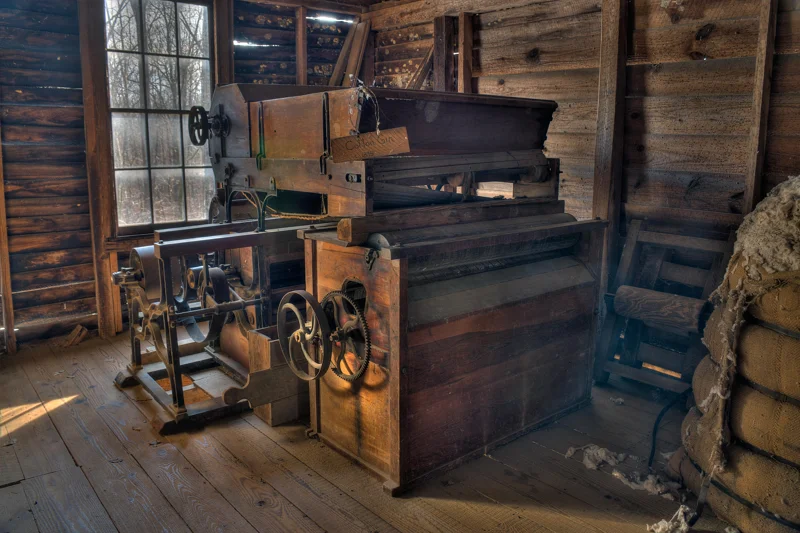 The Lummus cotton gin located at the Jarrell Plantation Historic Site in Georgia. Wooden contraption with metal machinery, housed what appears to be a wooden shed.