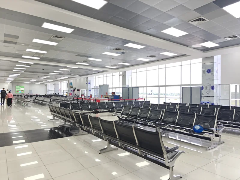 Black chairs at airport gate, mostly empty. Shiny floor.