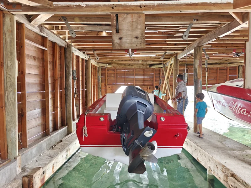 Back of a red boat with large motor within a wooden boathouse.