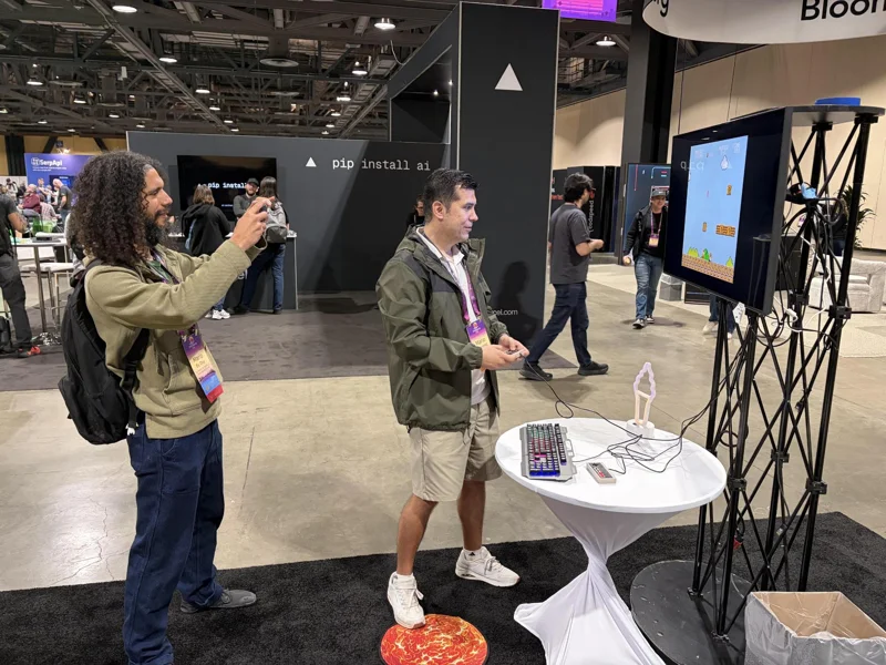 Man taking picture of another man playing Super Mario Bros at PSF booth.