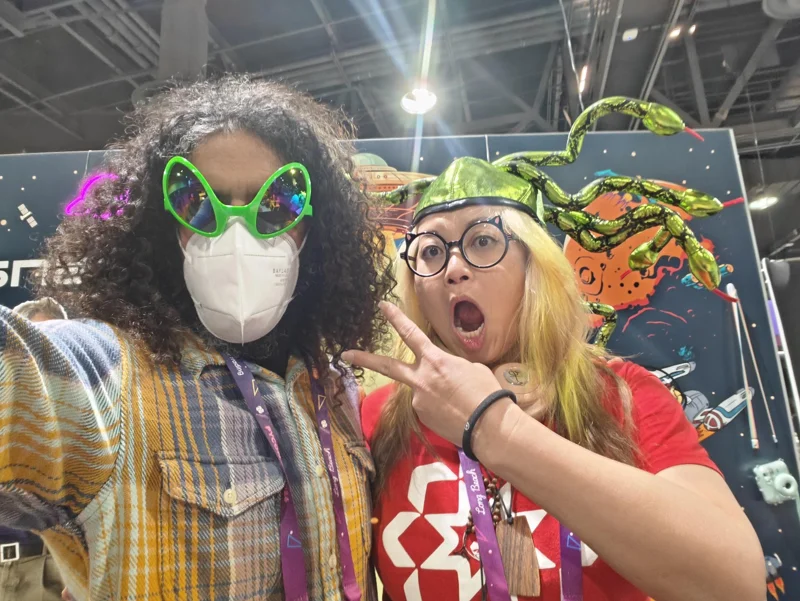 Selfie of man wearing glasses that look like alien eyes and a mask, with woman wearing a medusa hat with multiple snakes going every which way.