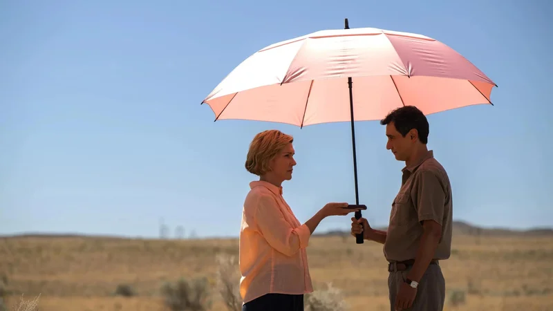 Carol and Manousos  standing under a pink umbrella in the desert.