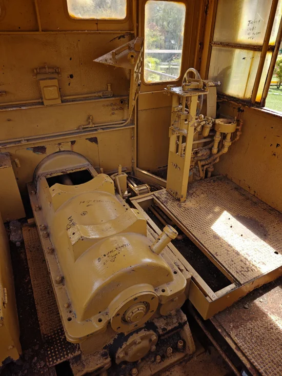 Inside old wooden train cabin, with sun beaming in, and trees outside of open windows.